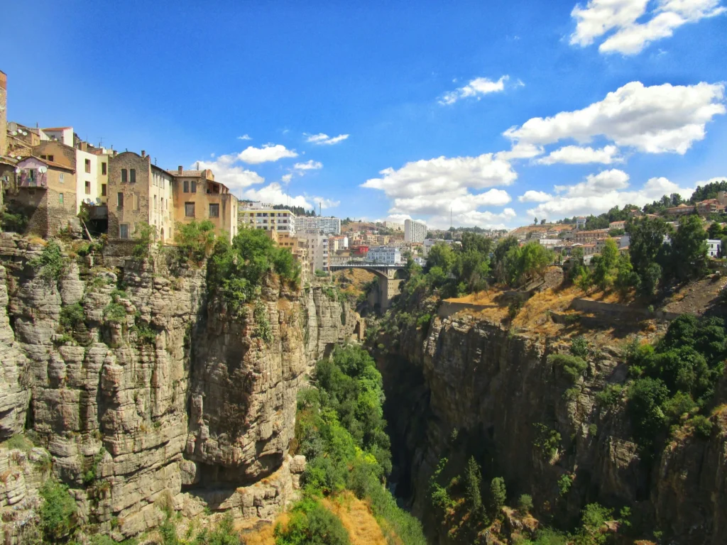 A town built into cliffs overlooking a deep gorge with green vegetation.