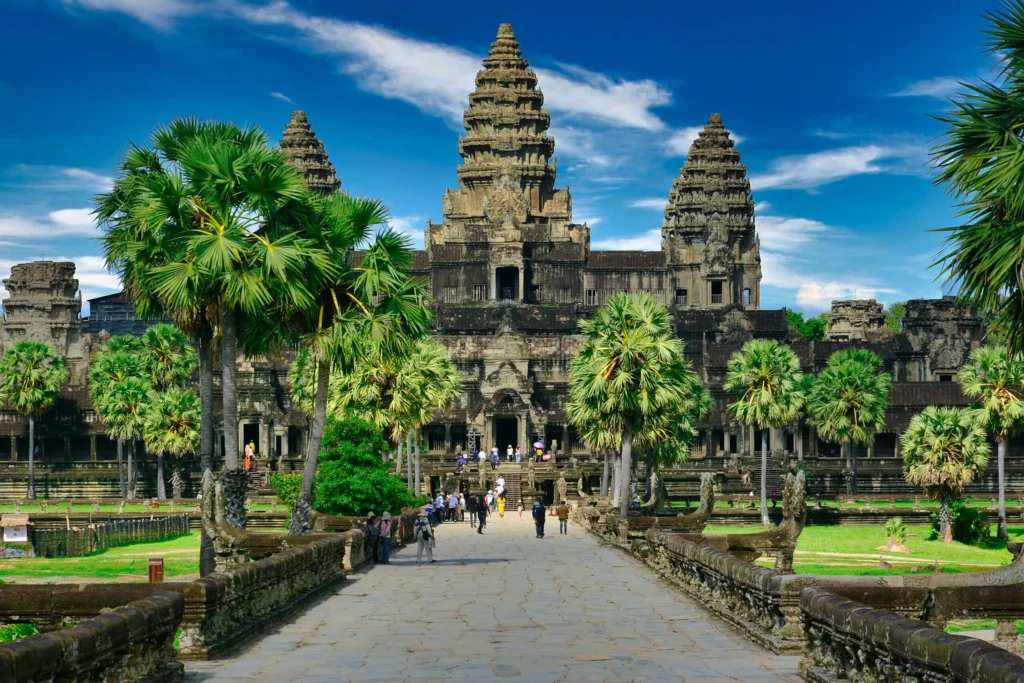 The grand Angkor Wat temple with its iconic towers, surrounded by lush trees and a clear blue sky.