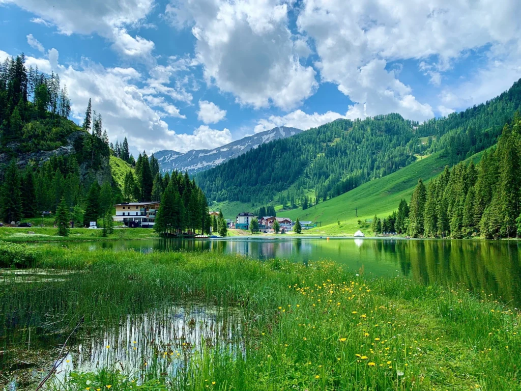 A serene mountain lake surrounded by lush green slopes under a partly cloudy sky.