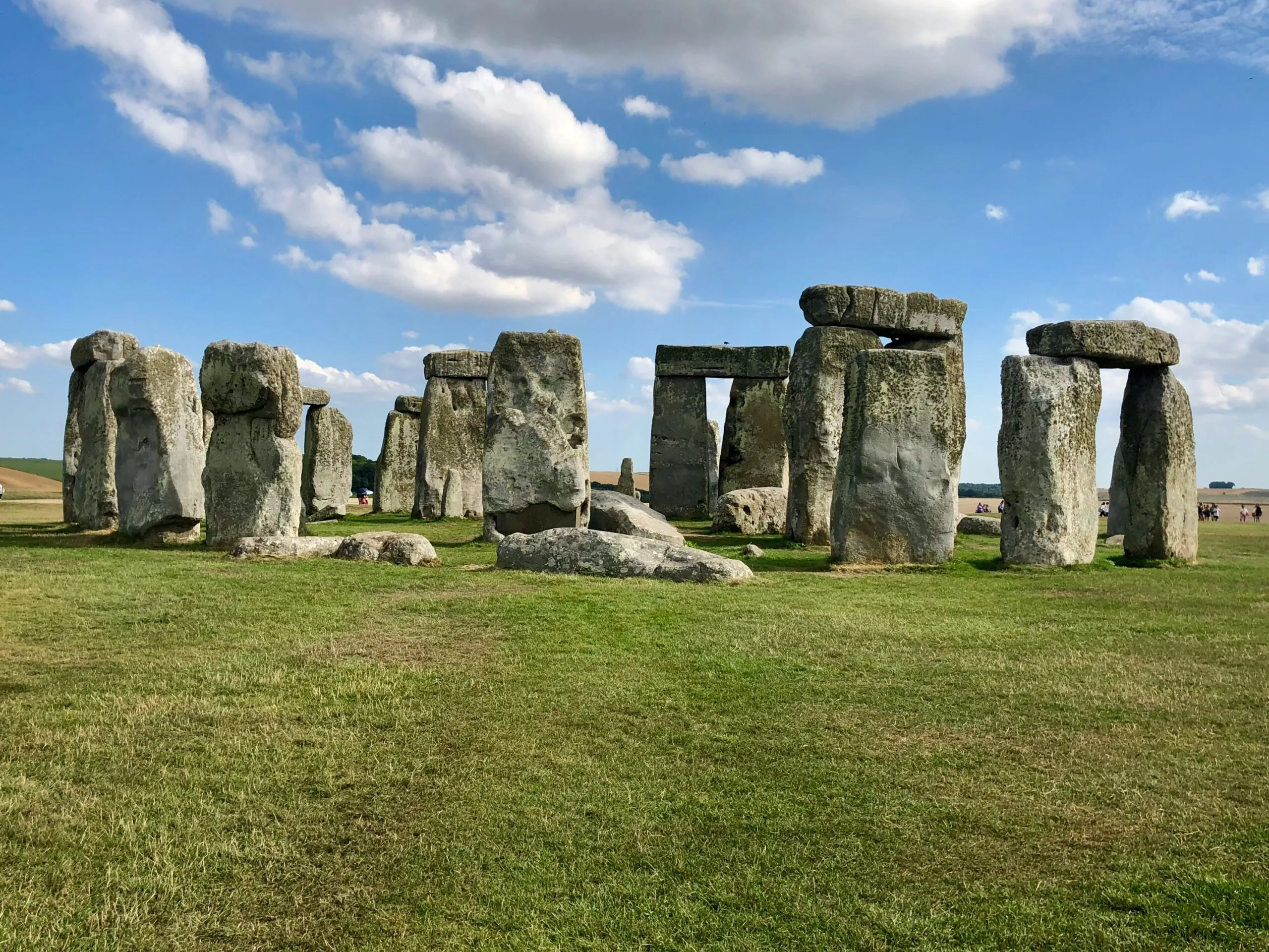 Stonehenge, an ancient monument of standing stones, under a blue sky with clouds.
