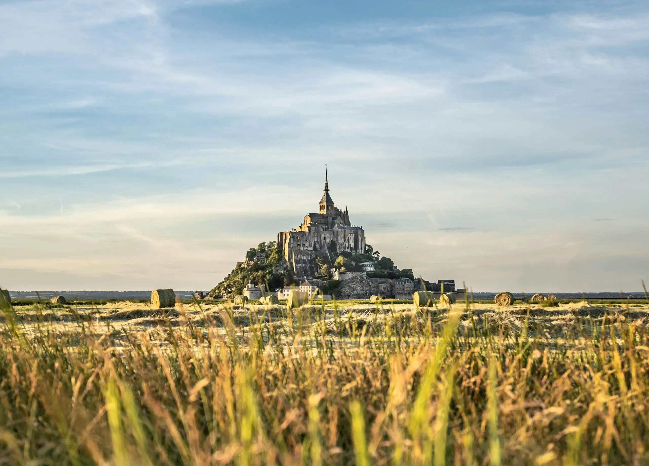 Mont Saint-Michel, a medieval abbey, rising from a flat plain.