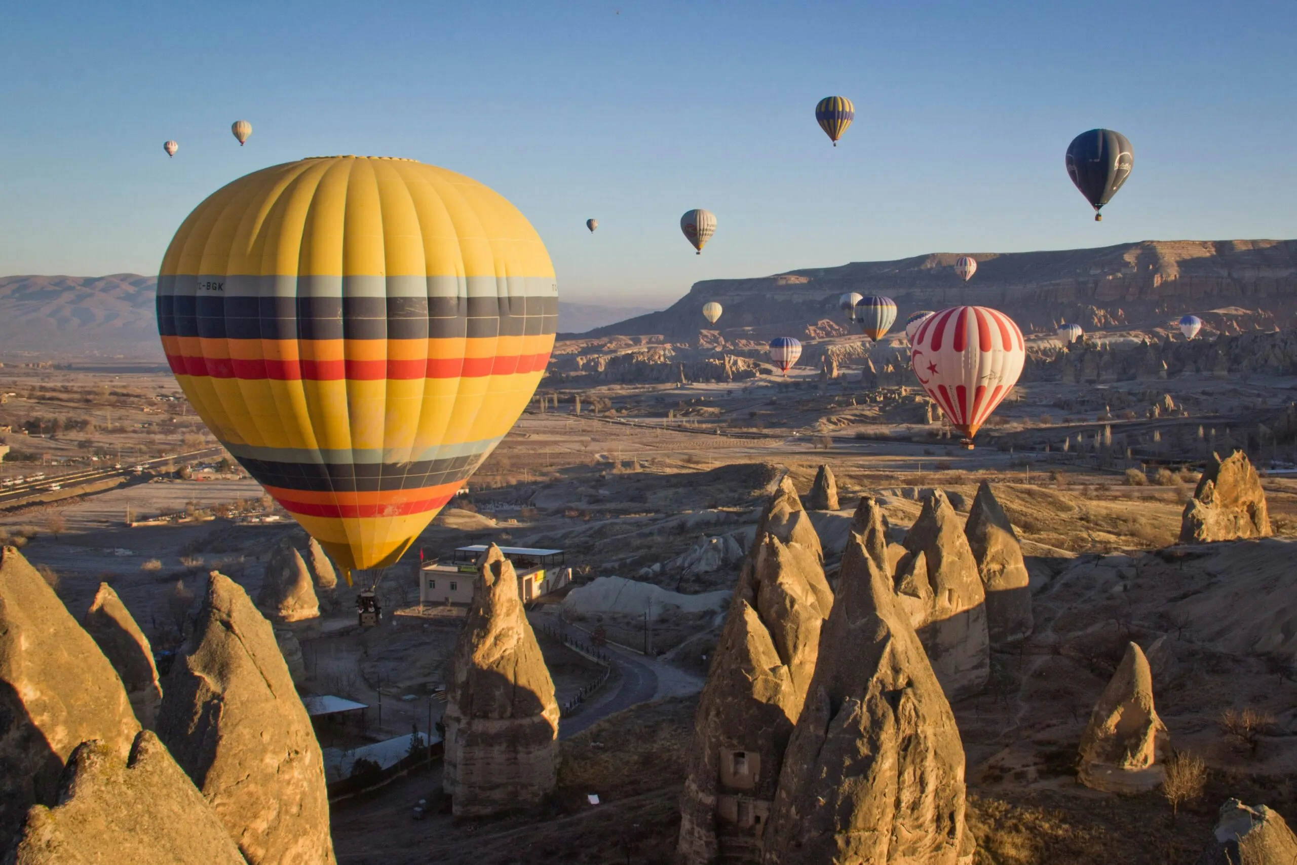Hot air balloons floating over unique rock formations in Cappadocia, Turkey.