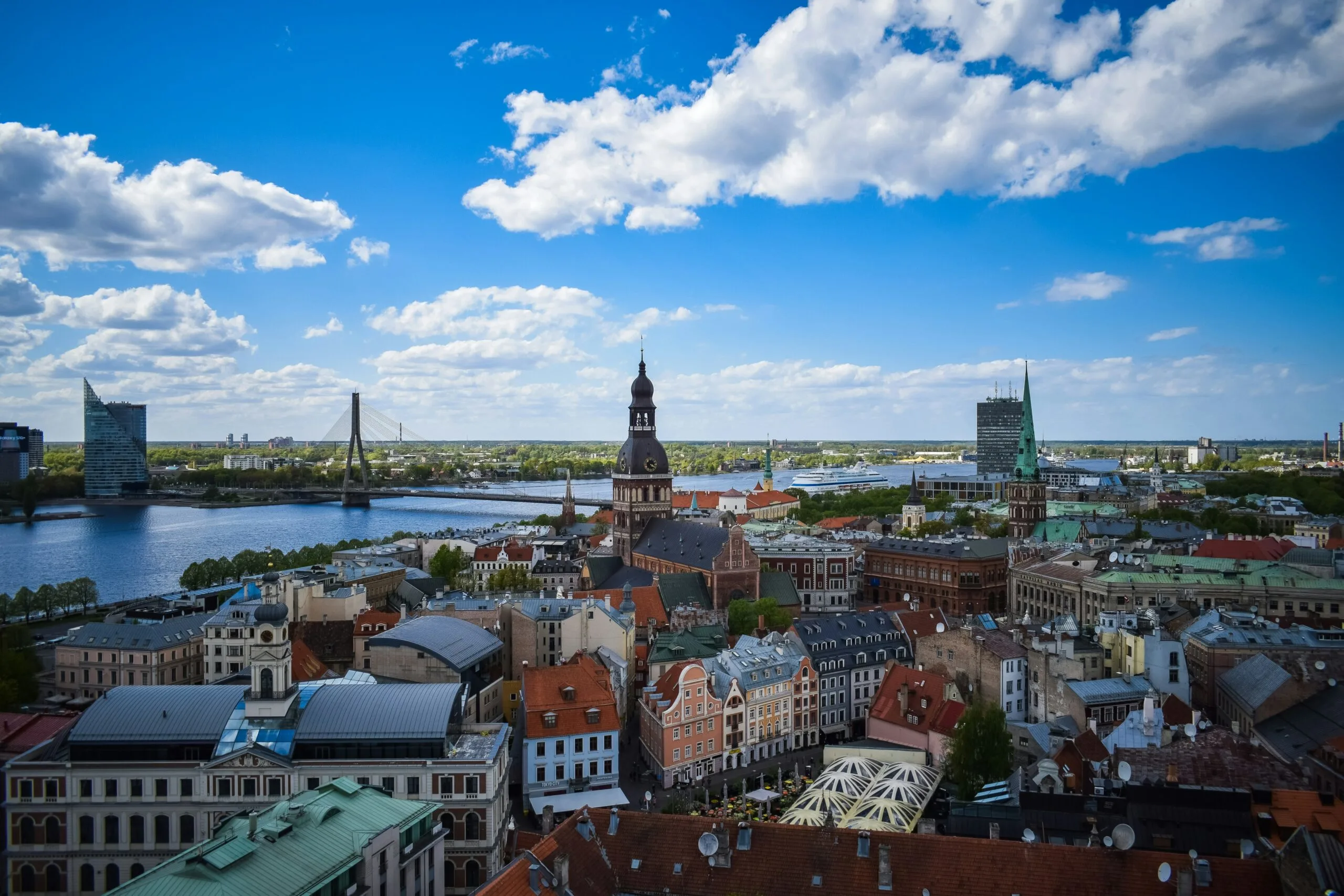 An aerial panoramic view of a city with a river and several bridges under a partly cloudy sky