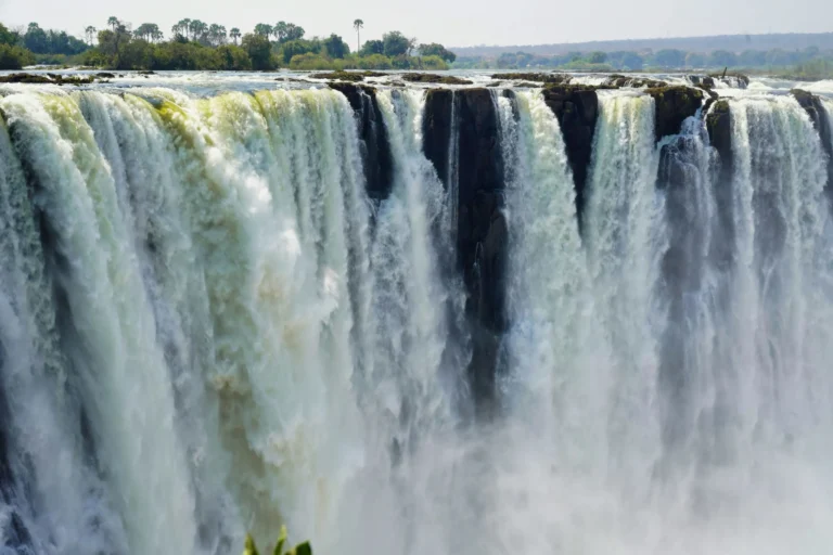 A wide waterfall cascades down, with mist rising from the bottom.