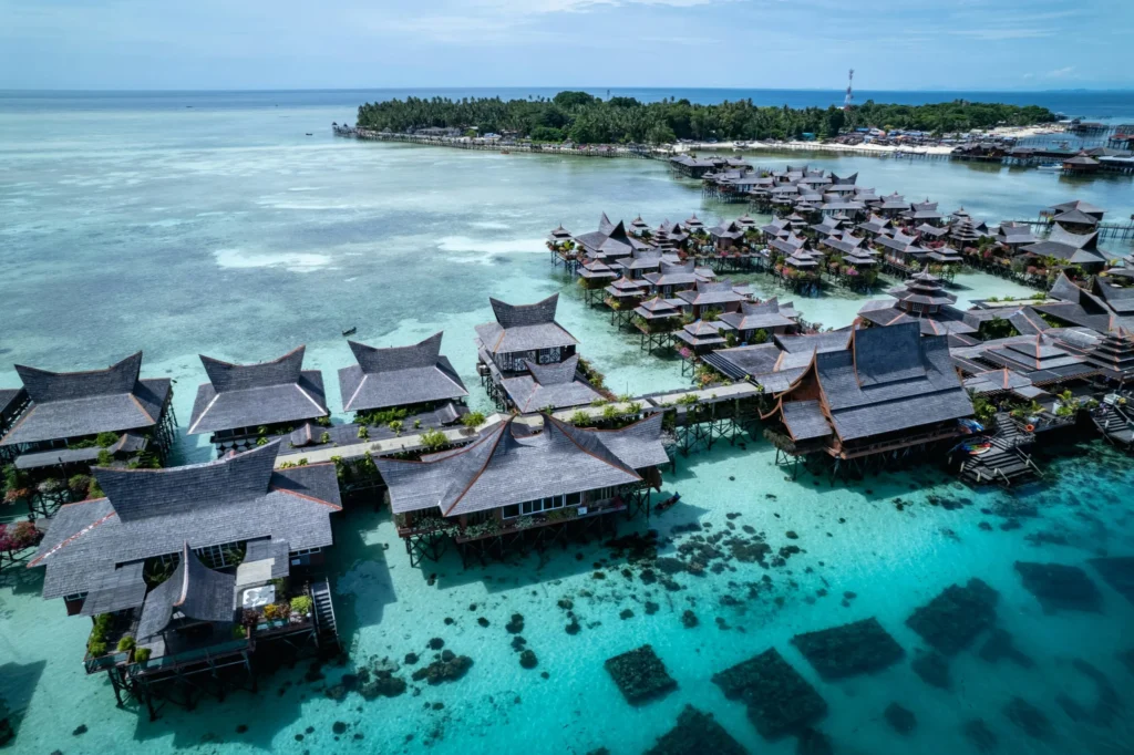 An aerial view of overwater bungalows extending into clear turquoise water.