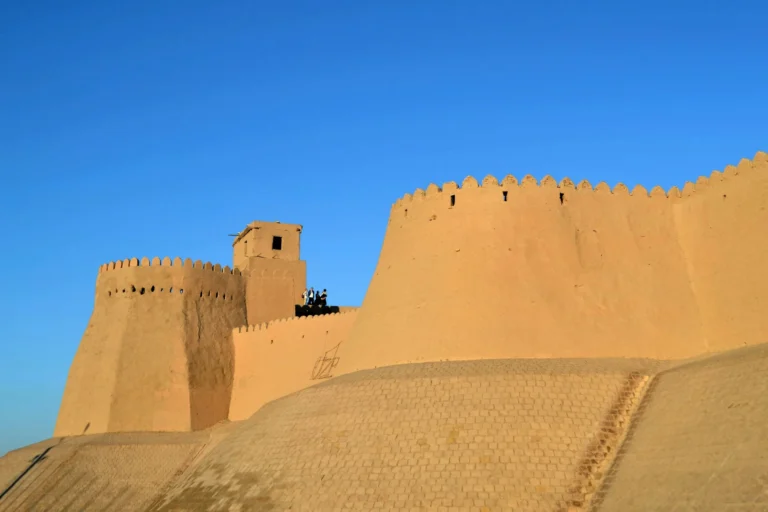 A large, ancient fortress with high, tan-colored walls under a clear blue sky.