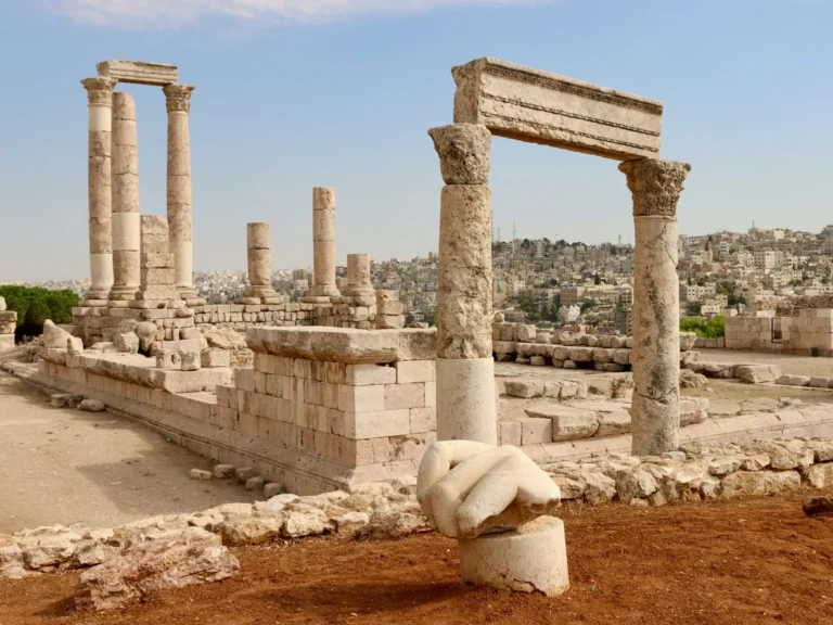 Ancient Roman ruins with tall stone columns and arches under a bright sky.