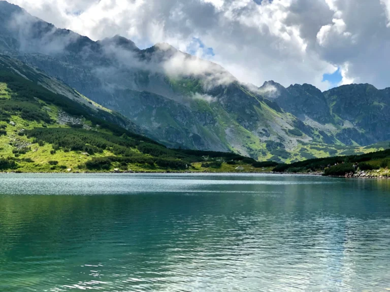 A serene mountain lake surrounded by peaks and clouds.