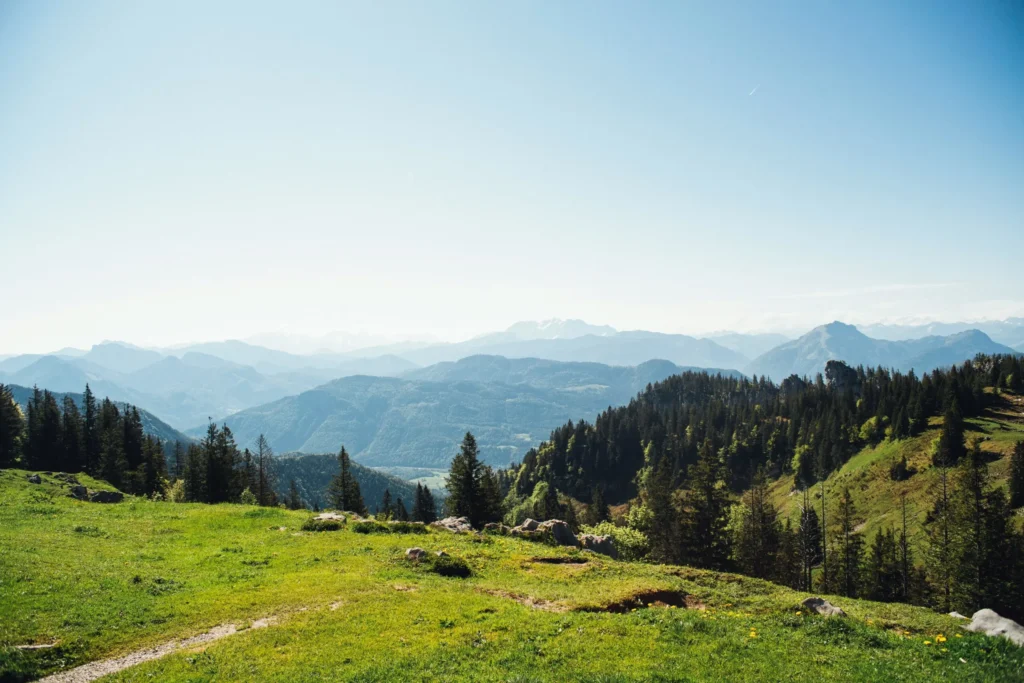 Rolling green hills and mountains under a clear blue sky.