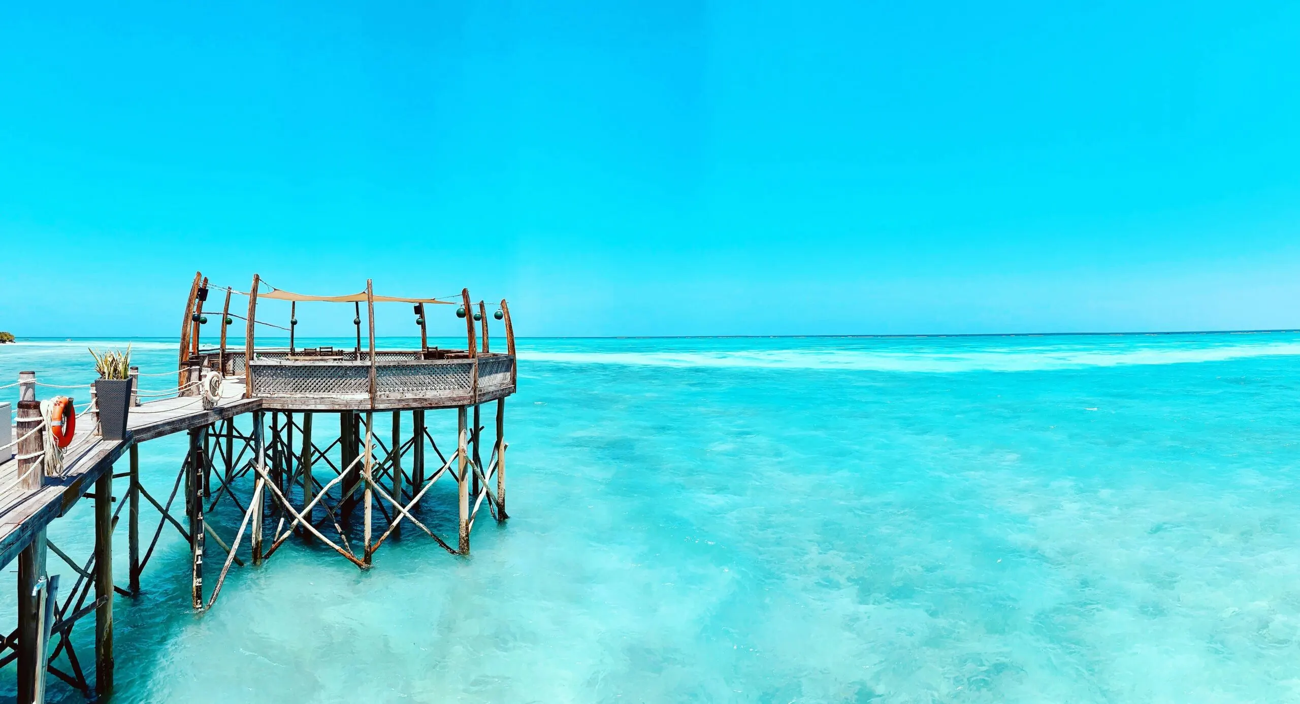 A wooden pier extends over clear, turquoise water.