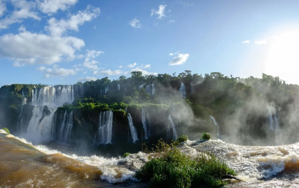 A panoramic view of Iguazu Falls, showcasing the immense power of the waterfalls and the surrounding lush rainforest.