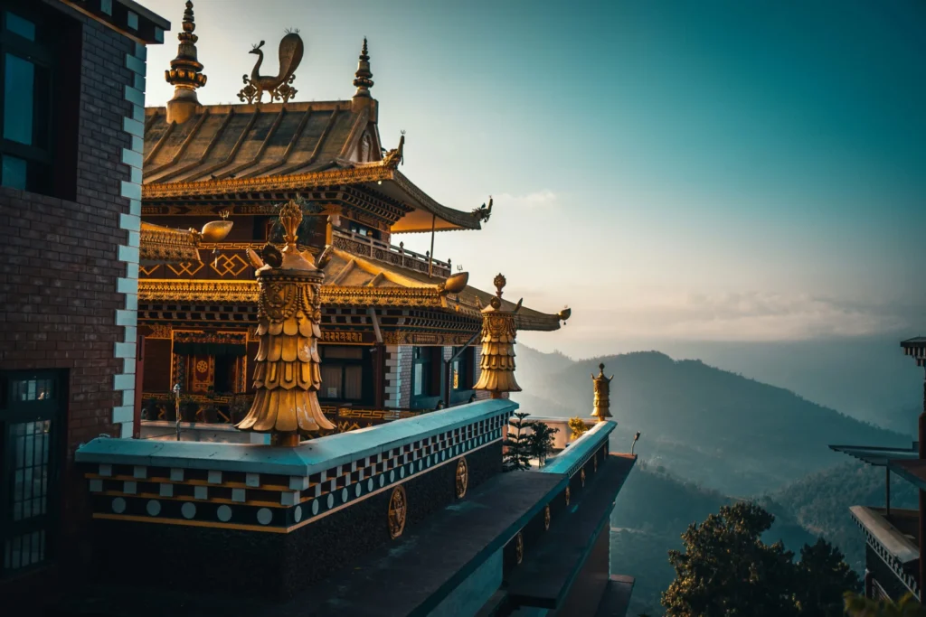 A traditional Buddhist temple with multi-tiered roofs, built into a mountainside, overlooking a vast landscape.