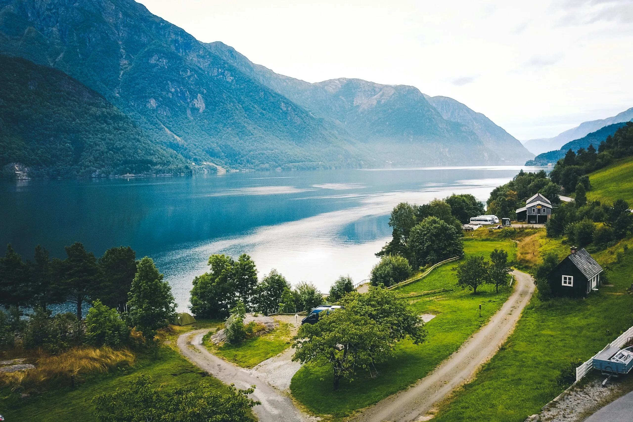 A serene fjord landscape with a body of water surrounded by green hills and scattered houses.