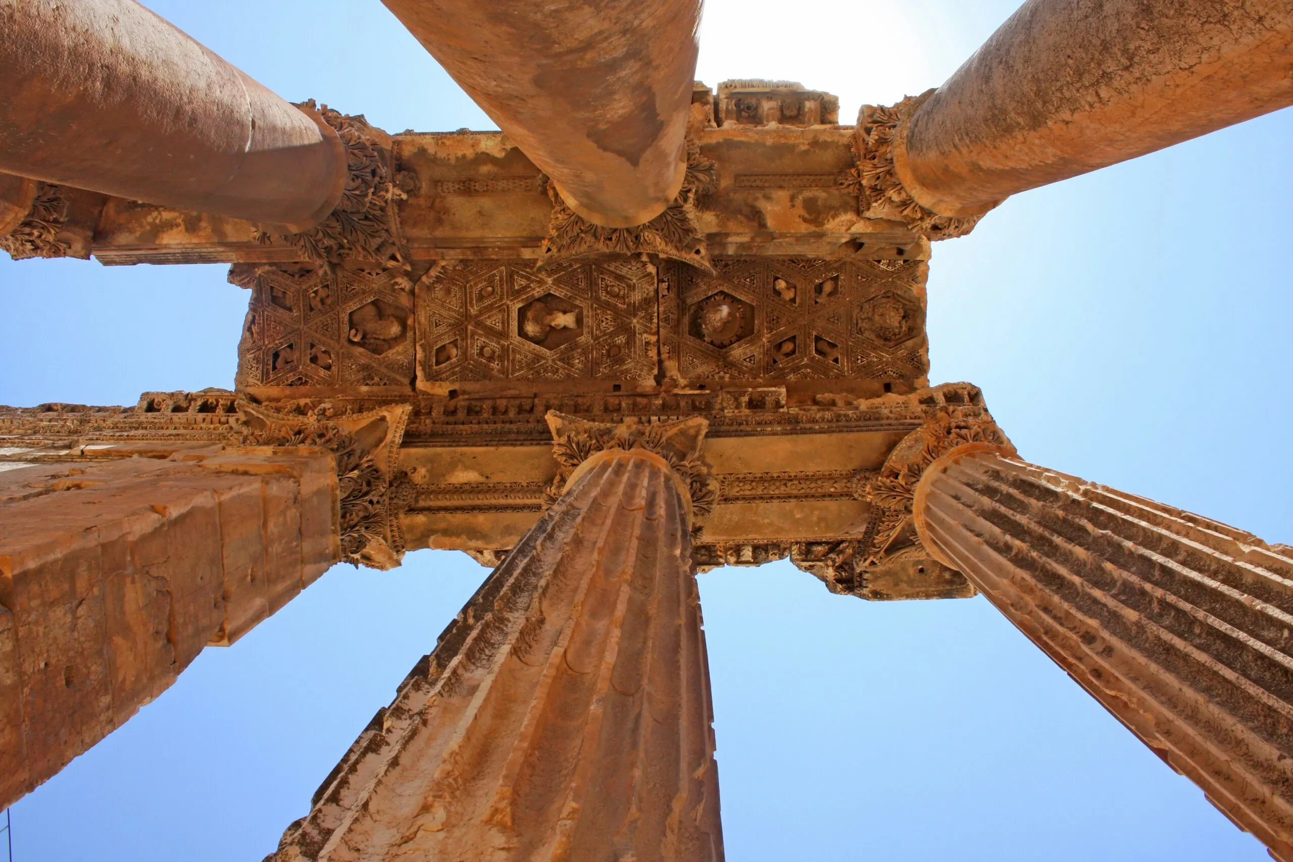 A low-angle view looking up at the ancient, weathered stone columns of a structure.