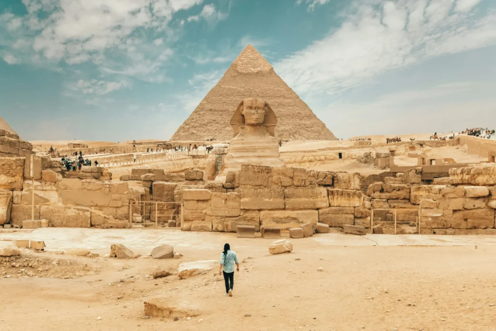 The Great Pyramid of Giza in a desert landscape, with a person standing in the distance.