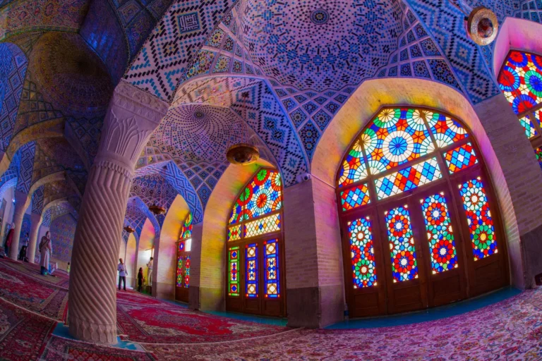 An interior view of a vibrant and colorful space with richly decorated arches, columns, and stained glass windows.