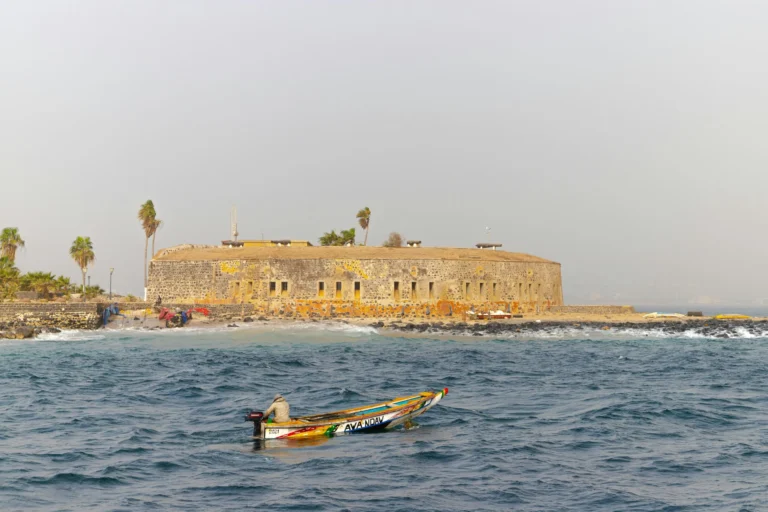 A historic stone fortress or island building surrounded by water, with a small boat nearby.