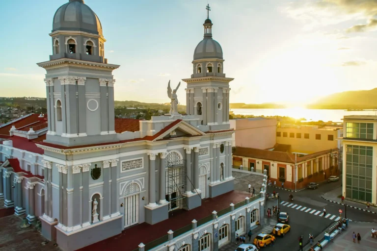 An aerial view of a large, ornate cathedral with two bell towers, bathed in the warm light of a sunset.