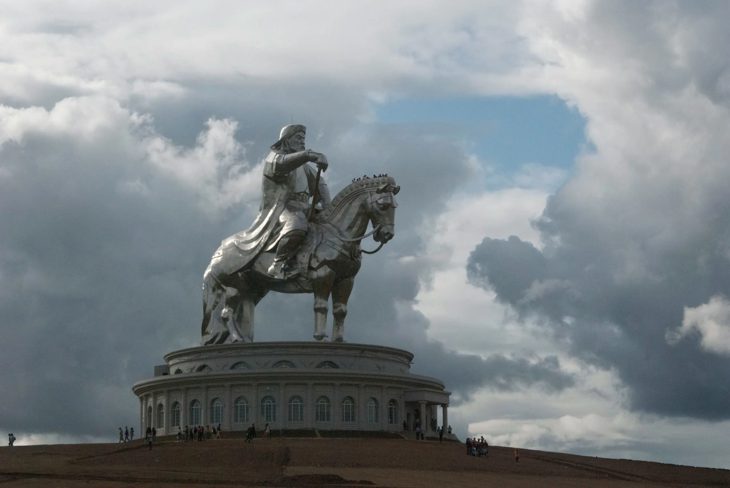 A towering equestrian statue of Genghis Khan under a dramatic cloudy sky.