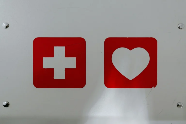A close-up of a white surface featuring two red square icons: one with a white cross (medical symbol) and the other with a white heart.