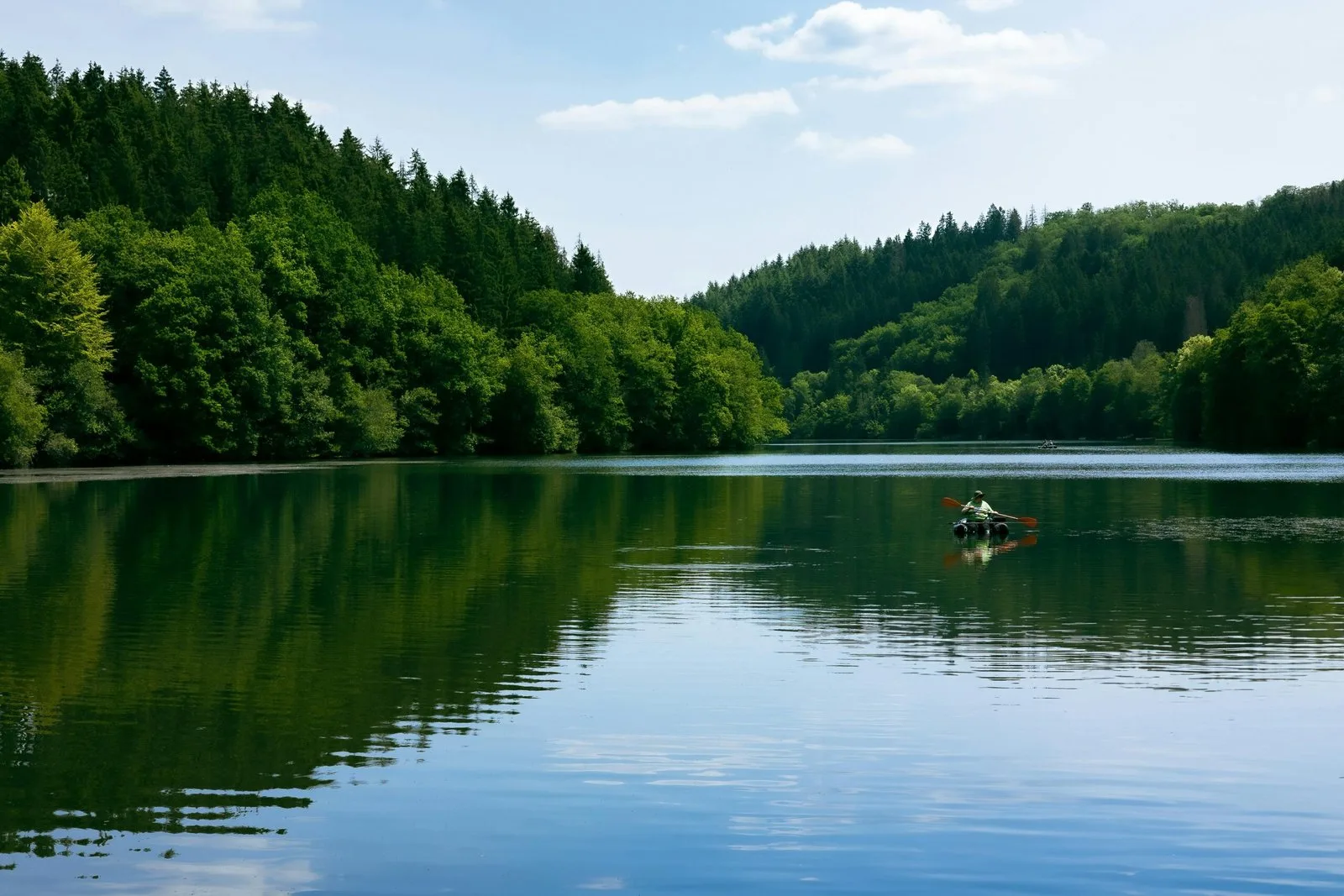 A scenic view of a calm lake surrounded by lush green hills.