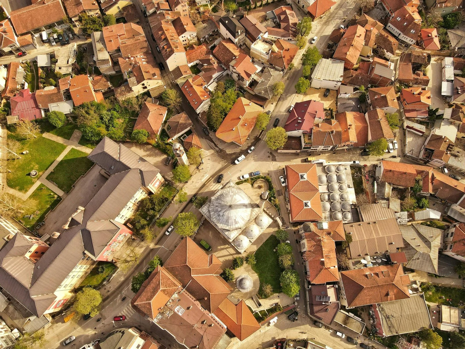 An aerial shot of a town with tightly packed buildings and orange-tiled roofs.