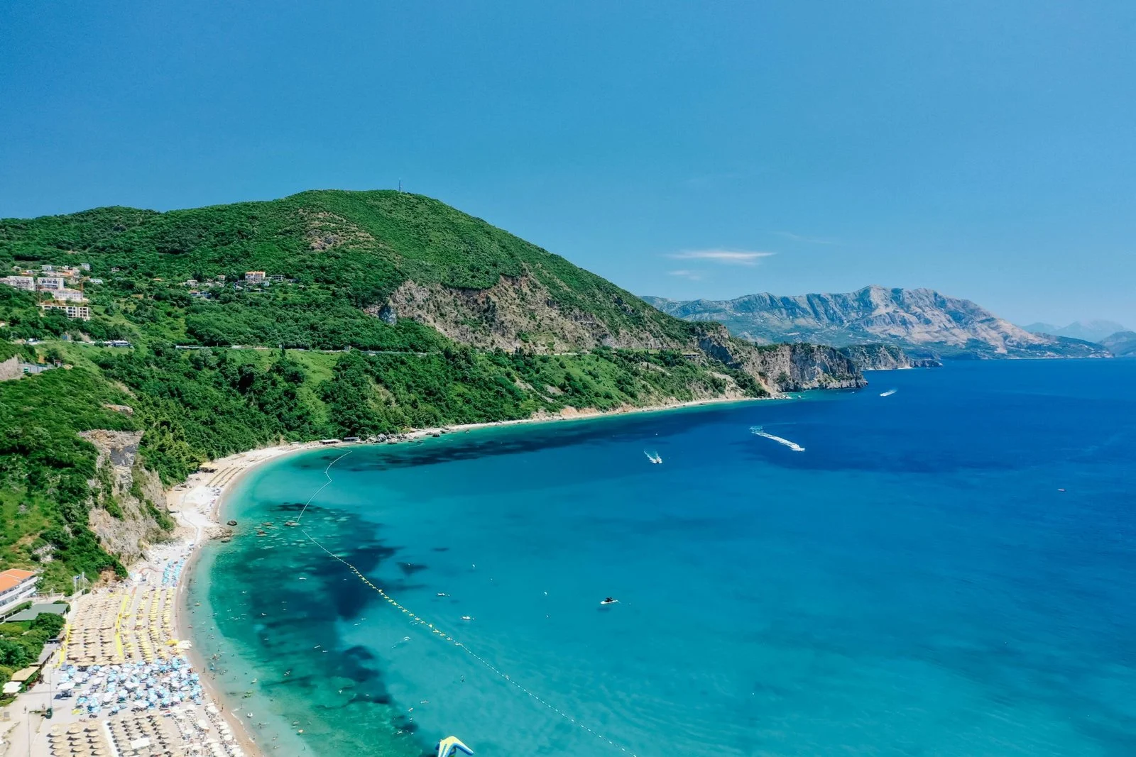 A view of a beautiful beach with turquoise water and lush green cliffs