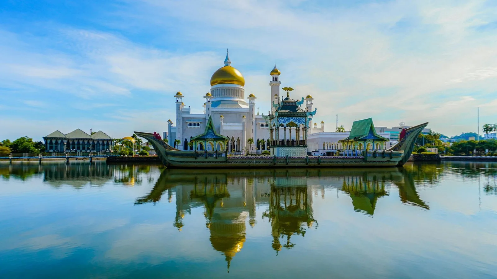 A beautiful mosque with golden domes, reflected in a body of water.