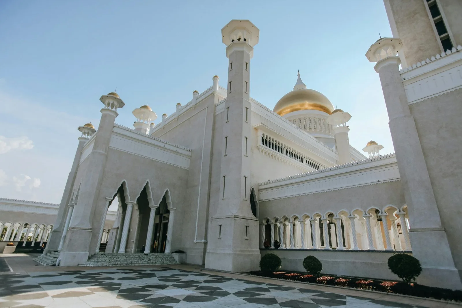 A close-up, low-angle shot of a white and gold mosque with intricate arches.
