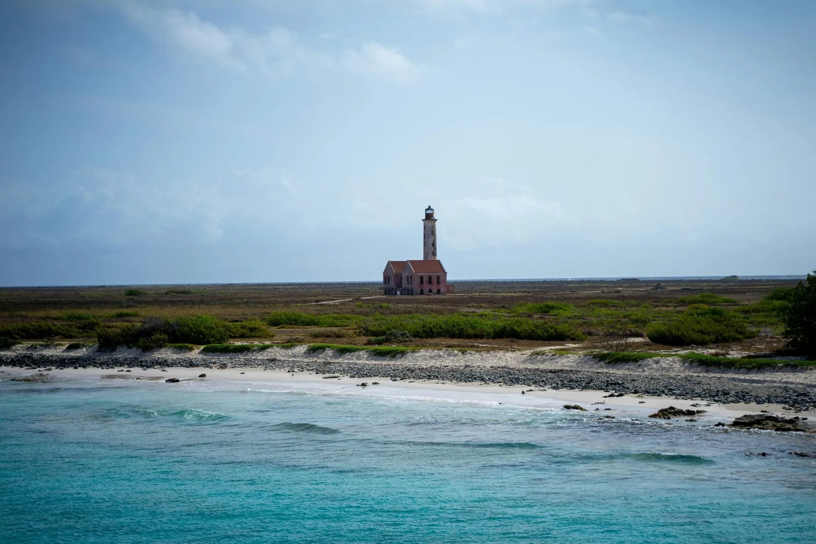 A lighthouse standing on a coastal plain near the ocean.