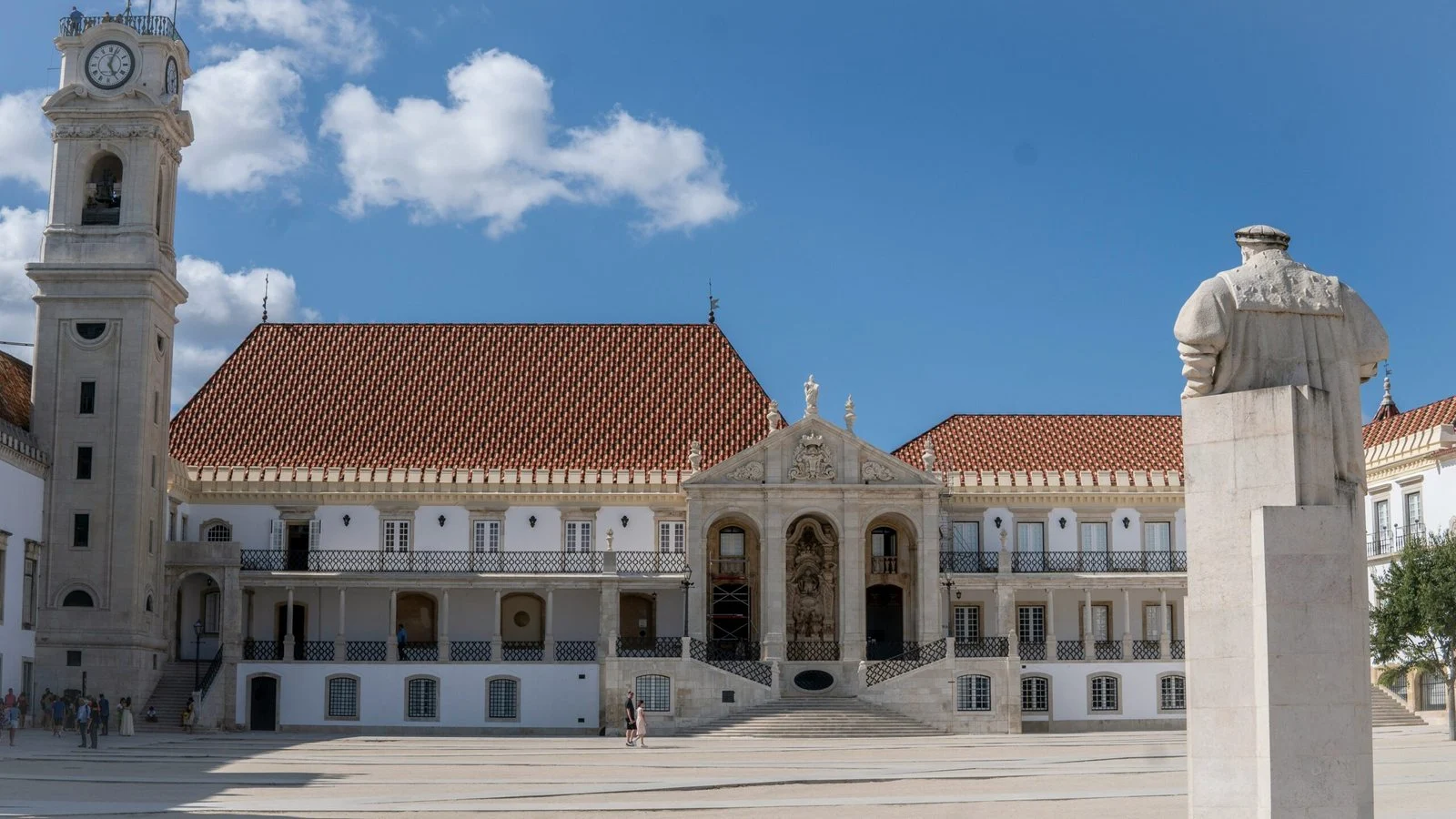 Off-season University of Coimbra courtyard in Portugal with historic white façades, red-tiled roof and almost empty square.