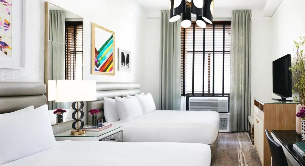 Minimalist boutique hotel room with two queen beds and city window, offering quiet off-season travel stay.