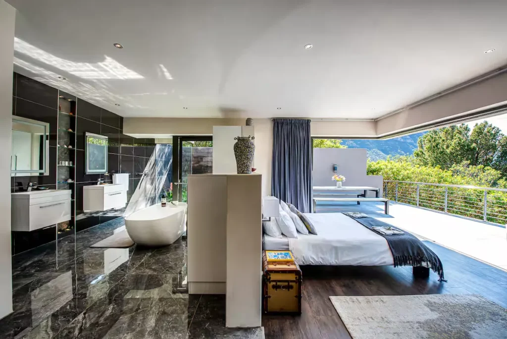 Modern luxury suite with open bathroom, freestanding tub and private terrace overlooking mountains in offseason retreat