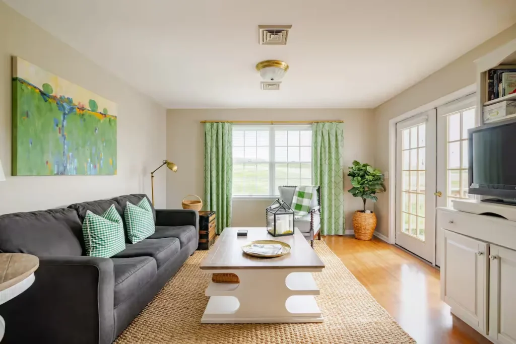 Cozy empty vacation rental living room with green decor and natural light through windows and doors in off-season calm