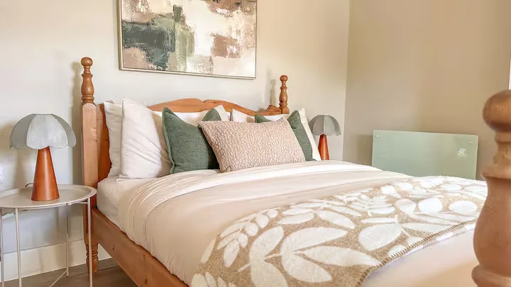 Cozy off-season travel bedroom with wooden bed frame, plush pillows and leaf-patterned throw in a serene retreat.