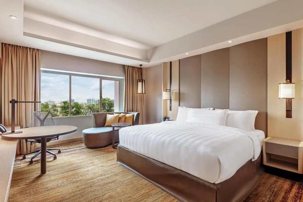Spacious modern hotel room for travelers with king bed, work desk and lounge seating by window in quiet off-season