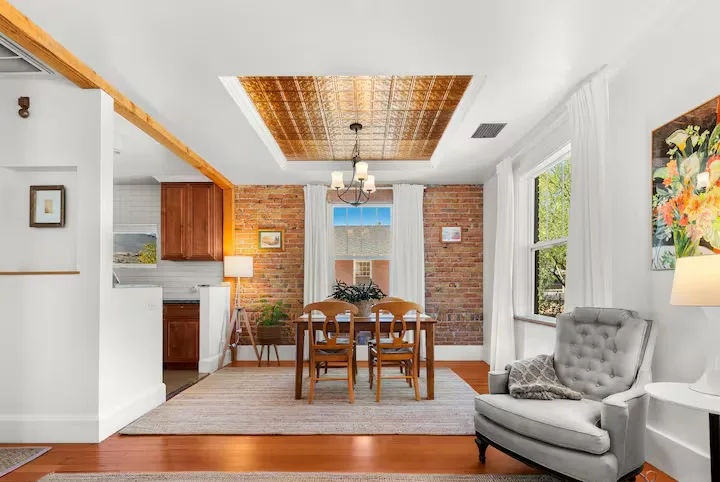 Cozy brick-walled dining room in a quiet vacation home, empty chairs and soft light evoke off-season calm.