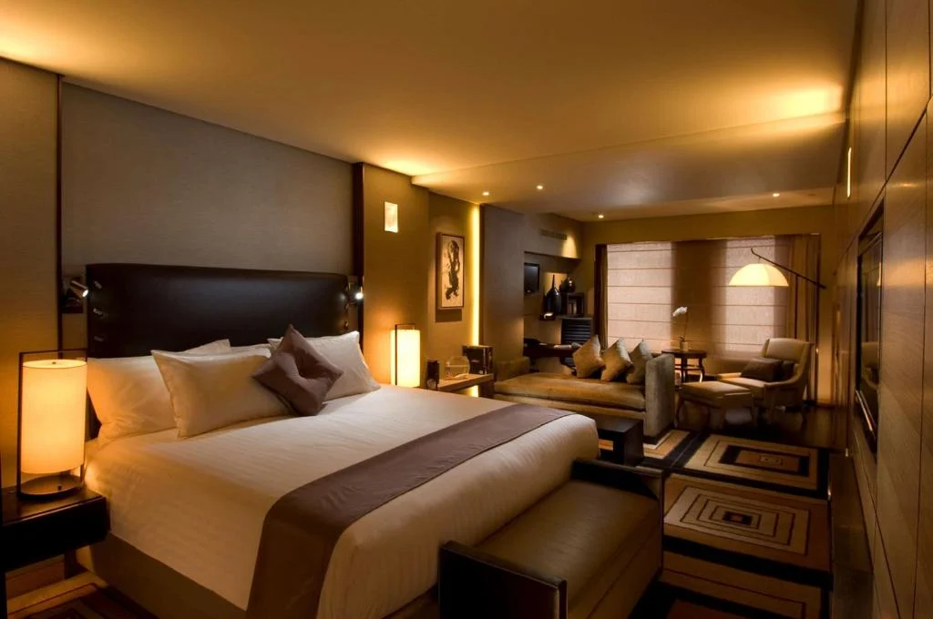 Off-season luxury hotel suite with king bed and lounge area, warm ambient lighting for quiet travel retreat