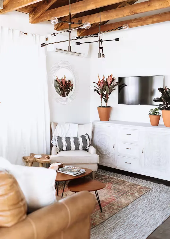 Cozy empty vacation rental lounge with wood beams, sofa, armchair, potted plants offering a quiet off-season retreat