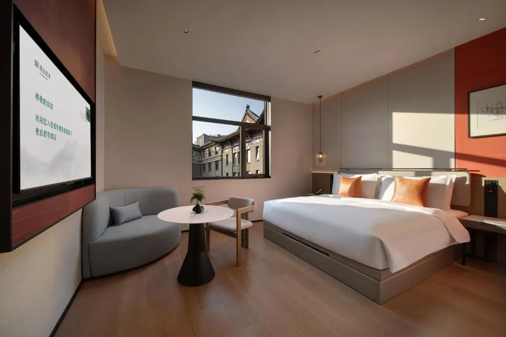 Serene urban boutique hotel room with king bed, lounge seating and rooftop view, offering quiet off-season city getaway.