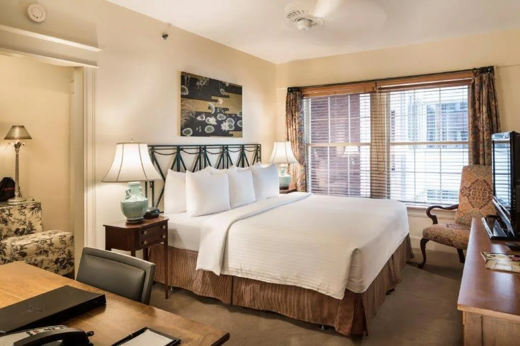 Cozy hotel bedroom retreat with king bed, wooden blinds and desk, offering a quiet off-season travel hideaway