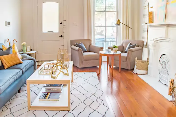 Sunlit, cozy vacation rental living room with armchairs, sofa, fireplace and decor, evoking a quiet off-season retreat