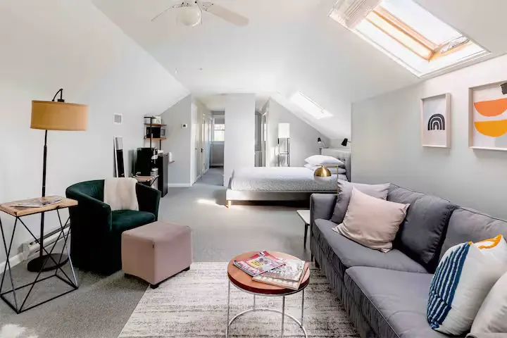 Bright loft-style hotel room with plush sofa, skylight windows and modern décor, a quiet off-season travel retreat.
