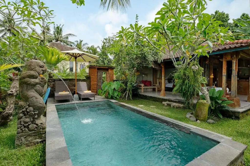 Tranquil off-season tropical villa pool with stone fountain, empty loungers and lush garden ambiance