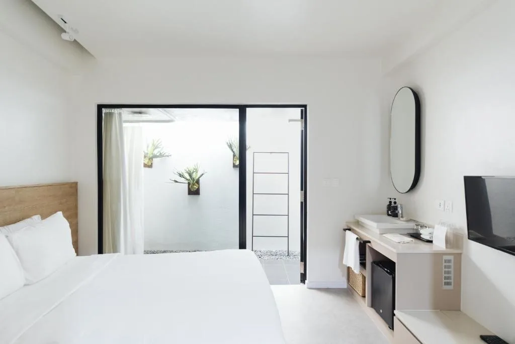 Minimalist hotel room with king bed and private outdoor patio, serene off-season travel retreat in peaceful settingően