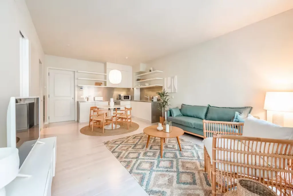 Bright, modern vacation rental living area with teal sofa, wicker chairs and dining table, off-season quiet retreat vibe.