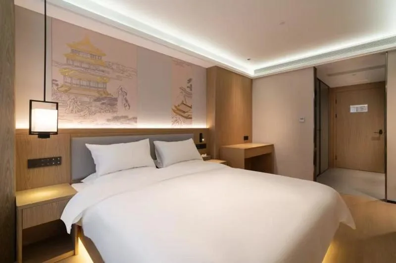 Empty modern hotel room with king bed, wood accents and soft lighting, evoking tranquil off-season travel calm.