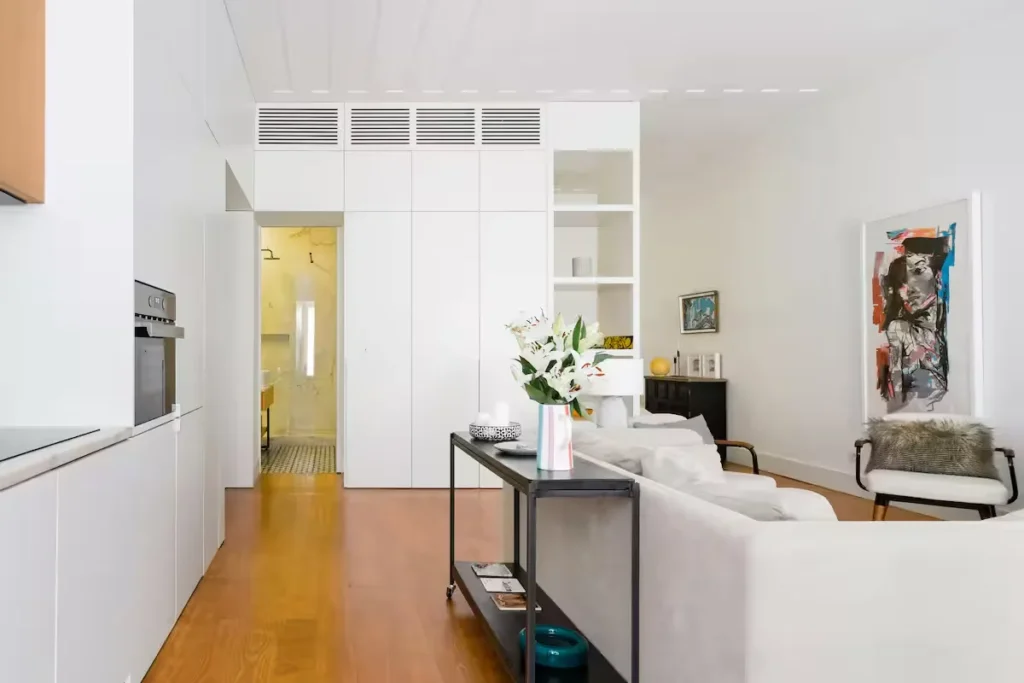 Empty minimalist travel apartment with white walls, wooden floors and modern art, offering a quiet off-season retreat.