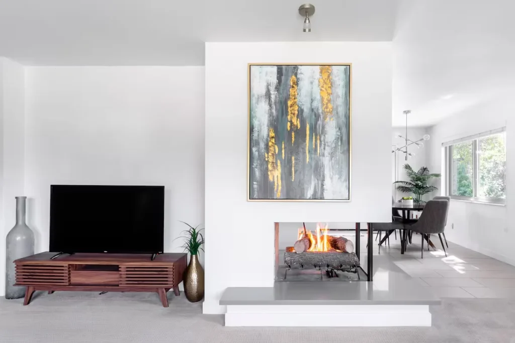 Quiet off-season vacation rental living room with cozy fireplace, modern TV console, teak accents and minimalist décor