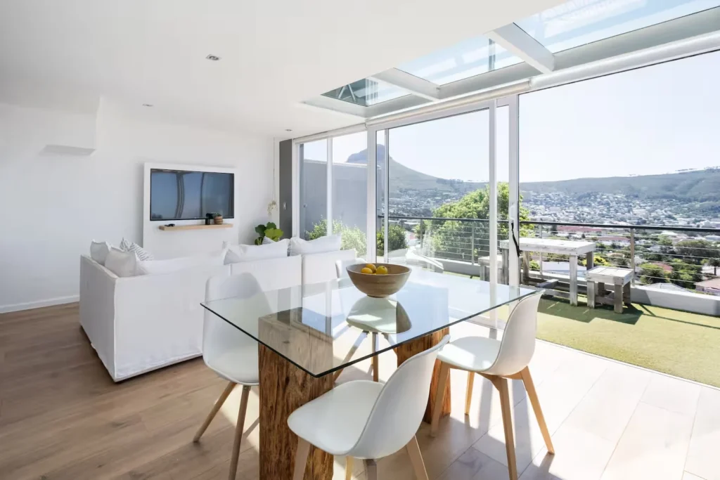 Bright modern vacation rental living area opens onto a quiet balcony with panoramic city and hill views in off-season calm